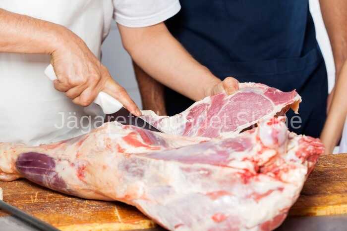 20023434 butcher cutting meat by colleague in butchery 4c697